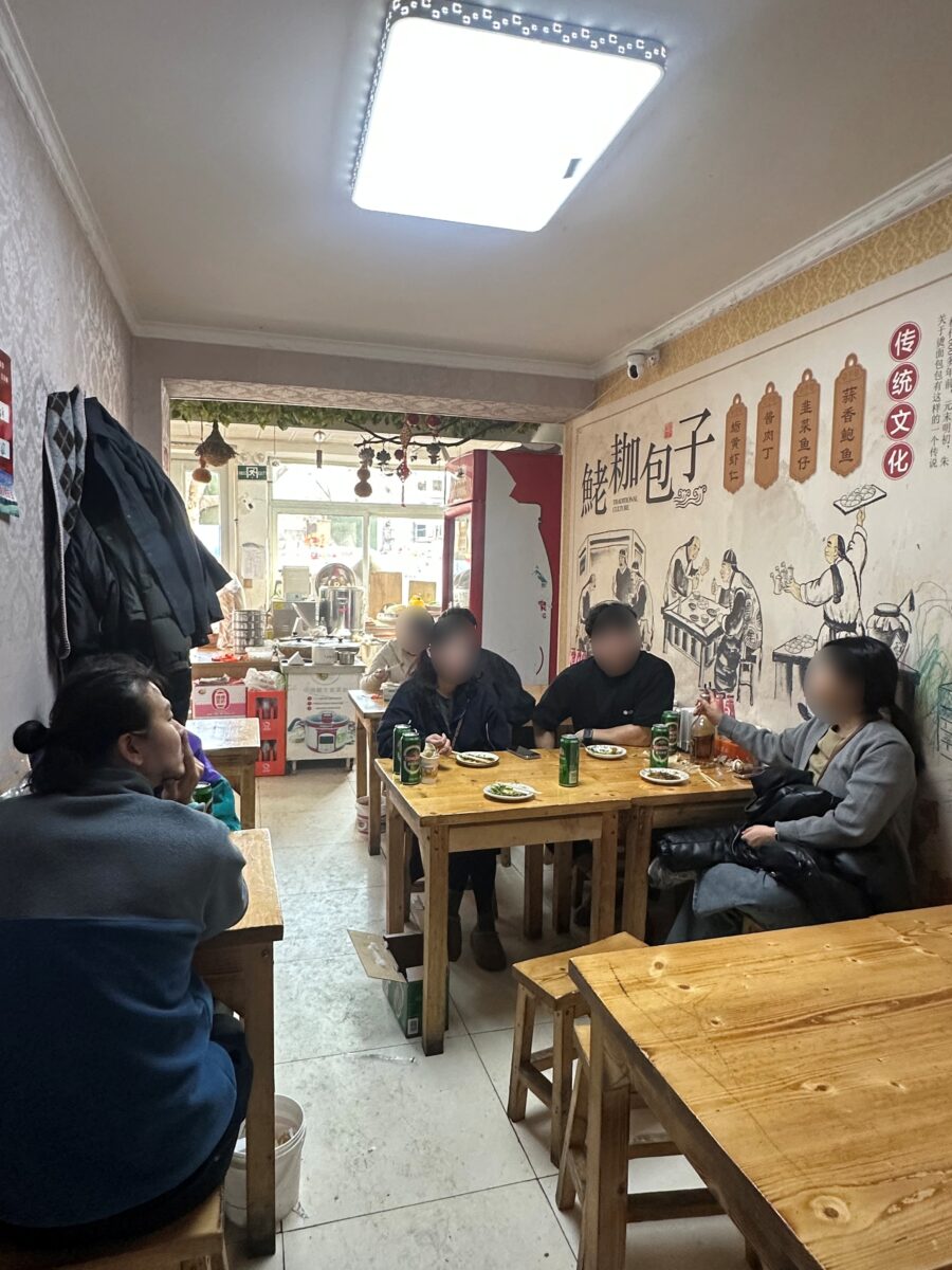 현지인들이 테이블에 앉아 식사를 즐기고 있는 노포 식당 내부 전경.