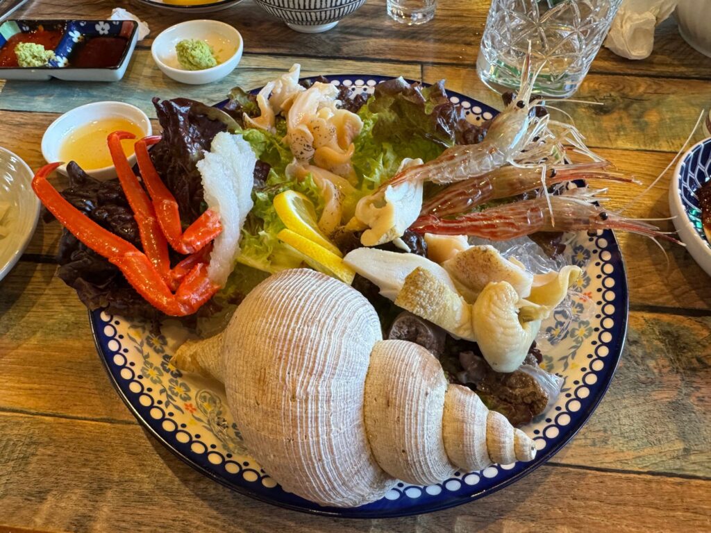 꽃새우, 백골뱅이, 홍게회가 담긴 접시와 각종 곁들임 반찬들.