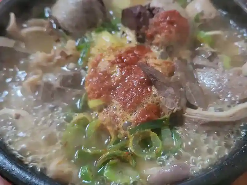 식당 테이블 위에 놓인 맥주와 밑반찬, 식사 중인 사람들의 모습.