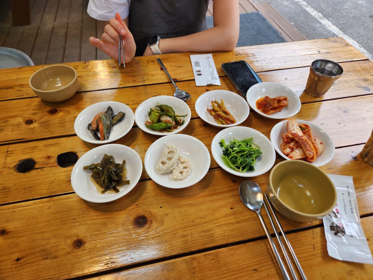 테이블 위에 정갈하게 놓인 여러 종류의 나물과 밑반찬 그릇들