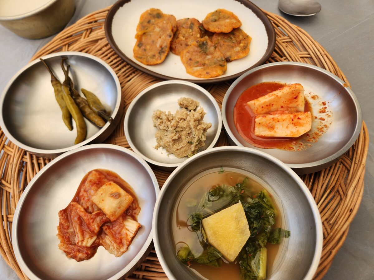 소반 위에 가지런히 놓인 김치전, 김치, 장아찌 등 밑반찬 그릇들.