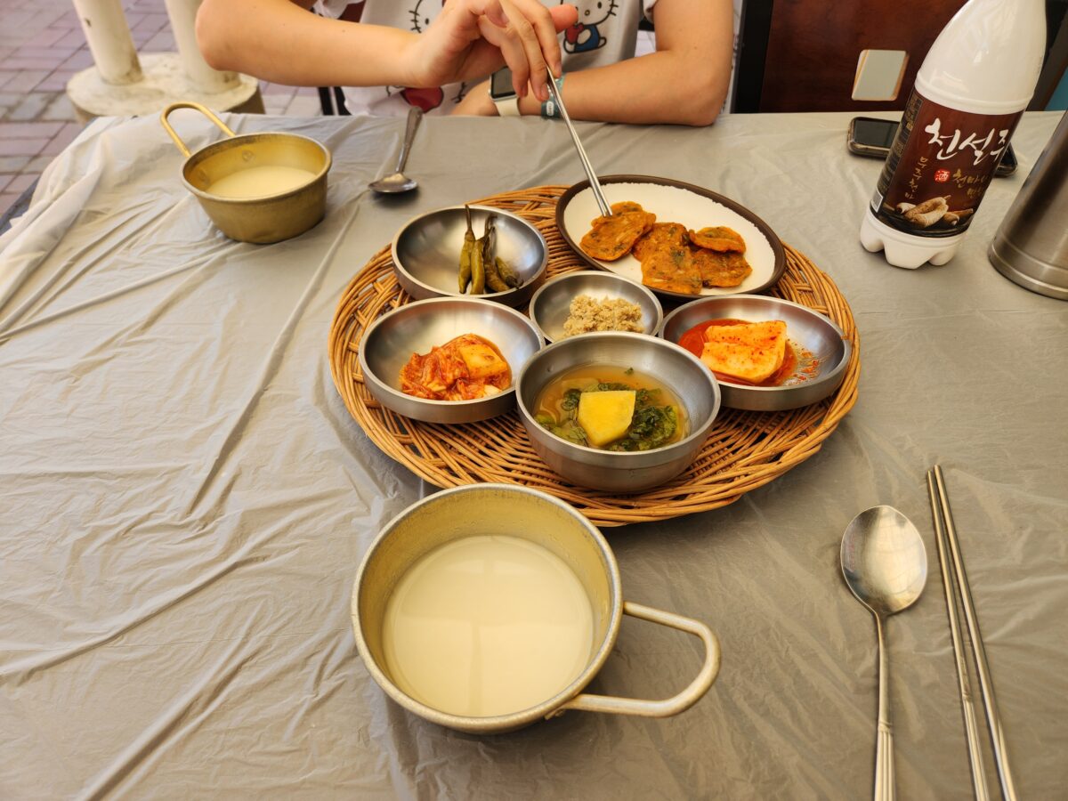 테이블 위에 차려진 어탕 수제비와 밑반찬, 막걸리 한 상차림.