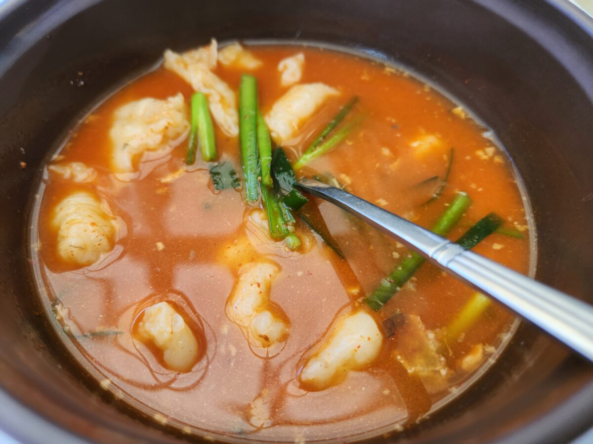 냄비 안에 담긴 붉은 국물의 어탕 수제비 근접 촬영.