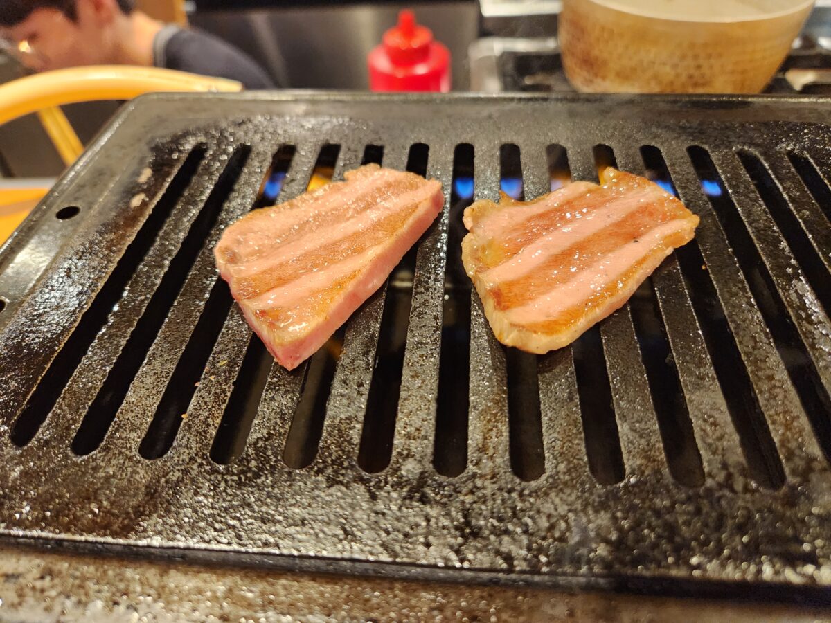 불판 위에서 맛있게 구워지는 고기 근접 촬영.