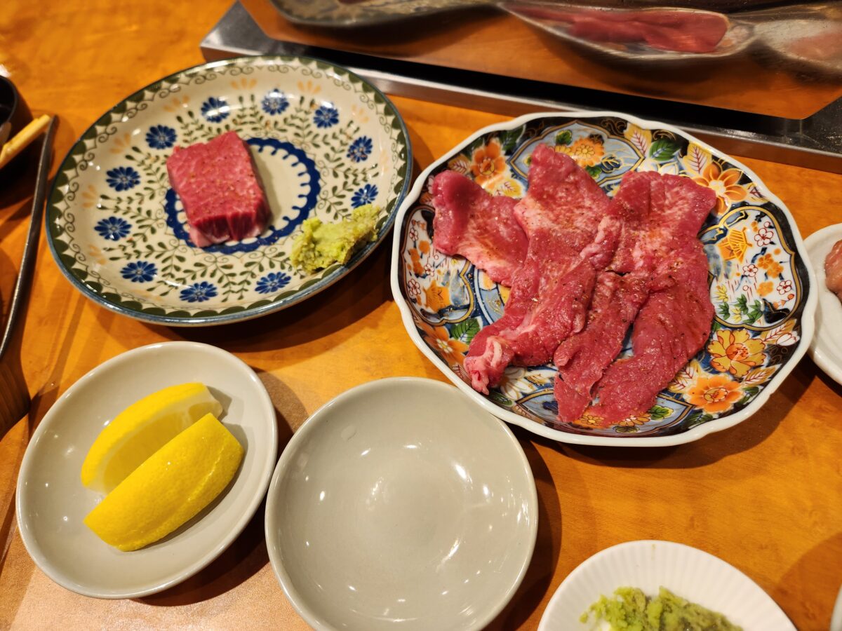 고기 접시와 레몬, 와사비 등이 세팅된 테이블.
