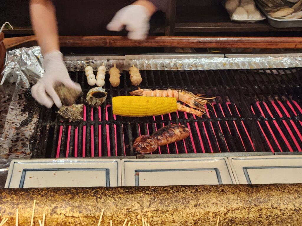 석쇠 위에서 새우, 옥수수, 소라 등이 구워지는 모습.