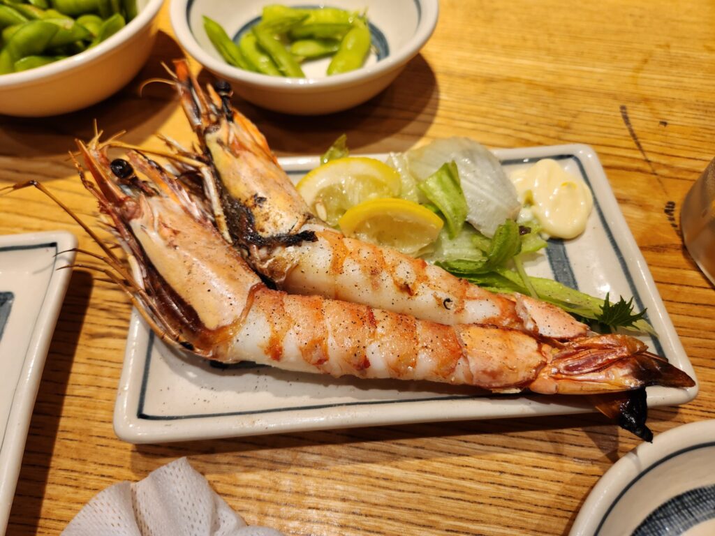 접시에 담긴 구운 새우와 레몬, 샐러드.