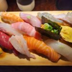 다양한 종류의 초밥이 나무 도마 위에 나열된 모습.