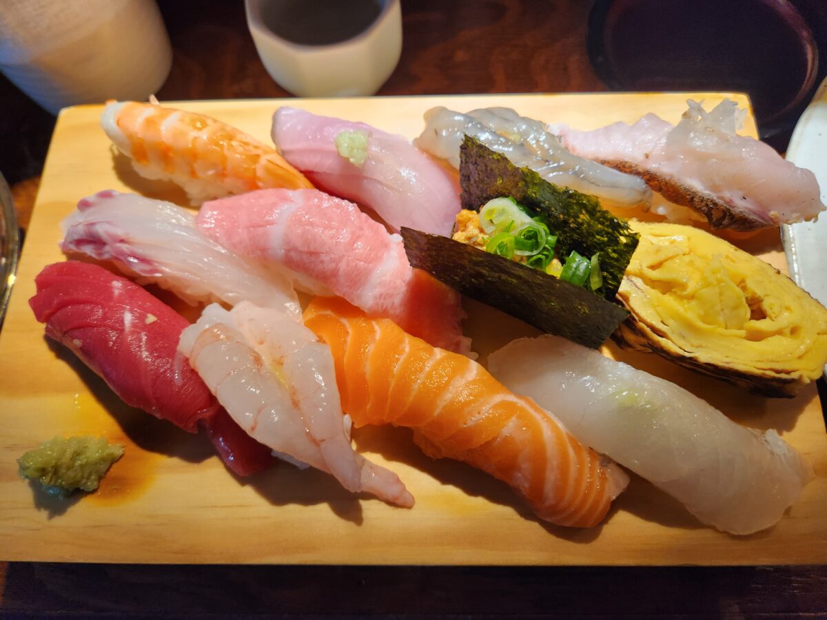 다양한 종류의 초밥이 나무 도마 위에 나열된 모습.