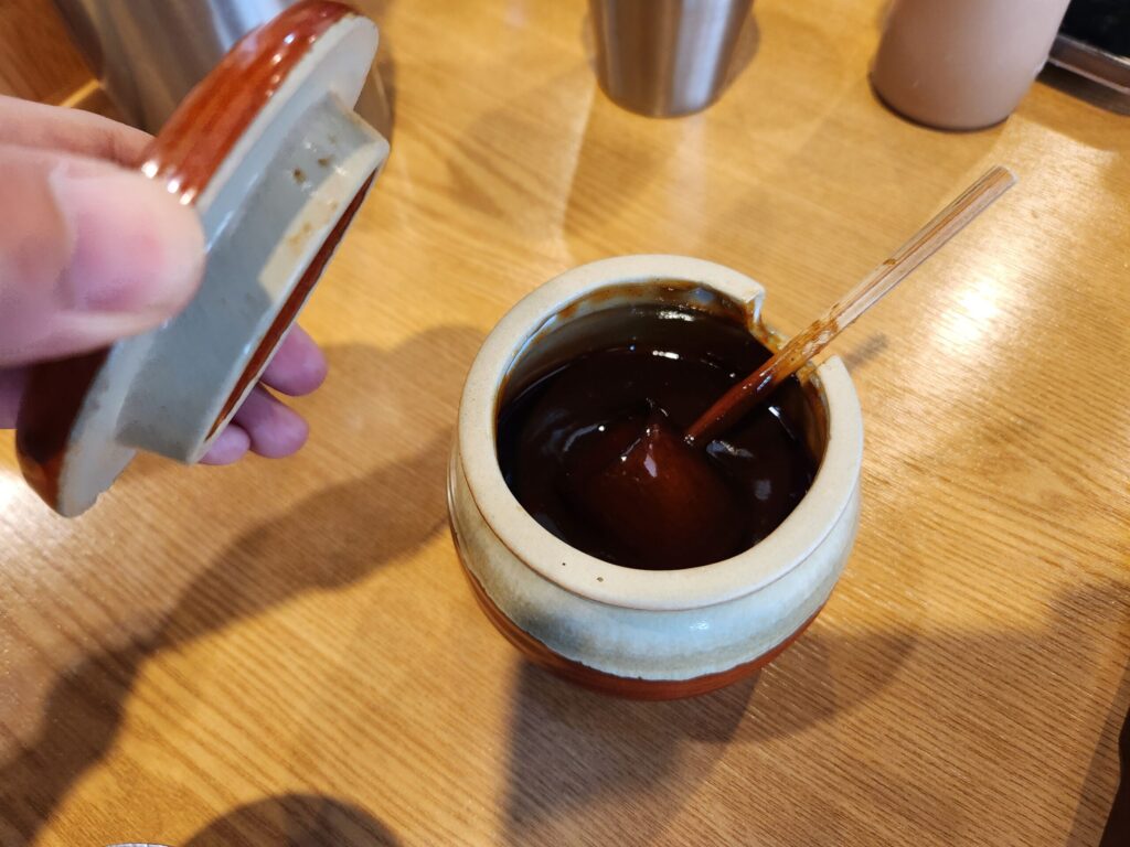 돈까스 소스 그릇과 뚜껑을 들고 있는 손.