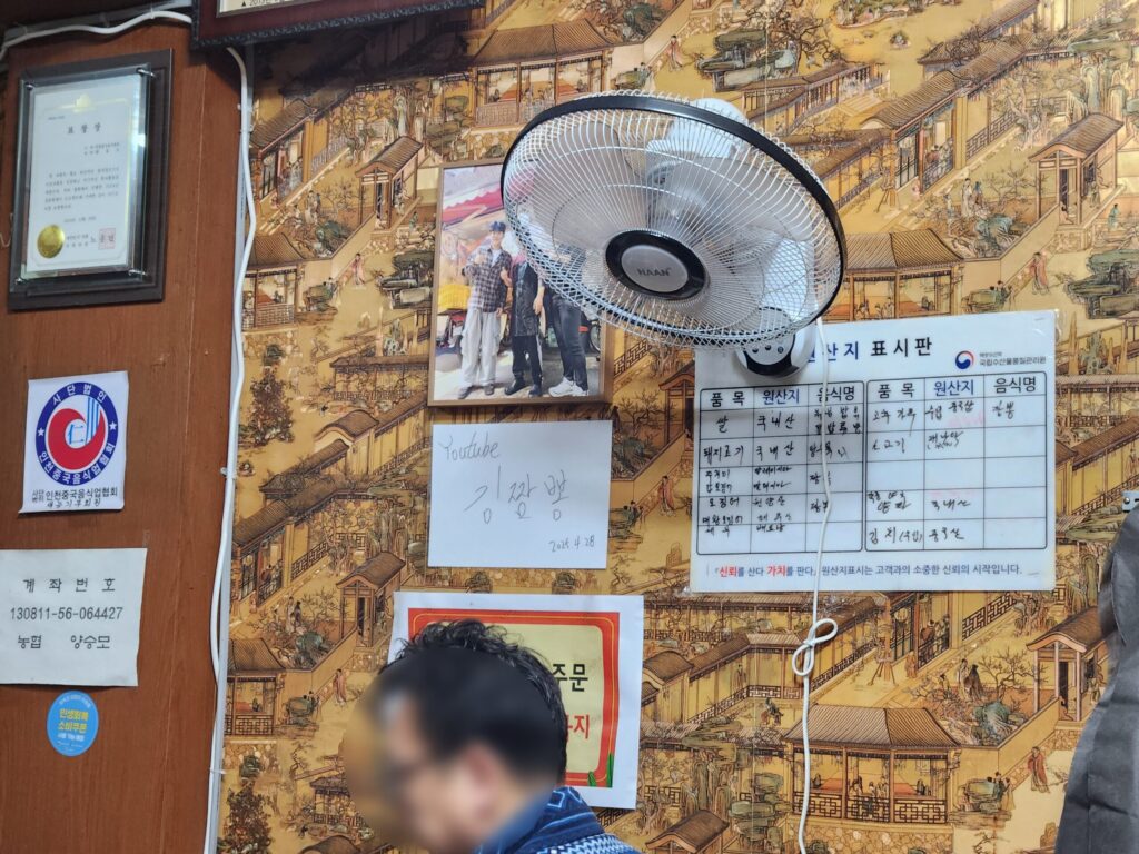 매장 벽면에 걸린 김짬뽕 유튜버의 사인과 원산지 표시판.
