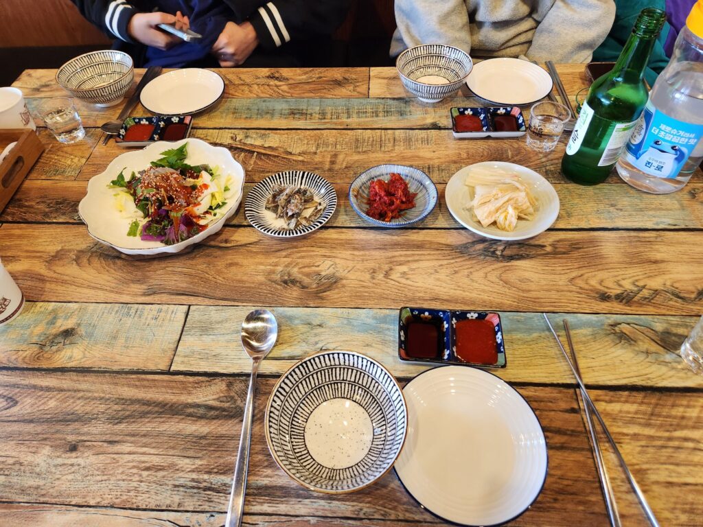 테이블 위에 차려진 명태무침, 멸치볶음, 쥐치회무침 등의 기본 반찬.