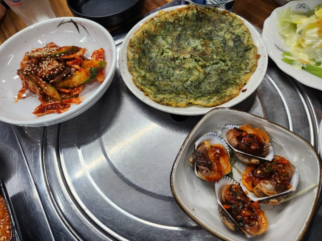 파래전, 복어껍질무침, 피꼬막 등 다양한 스끼다시가 원형 테이블 위에 차려진 모습.