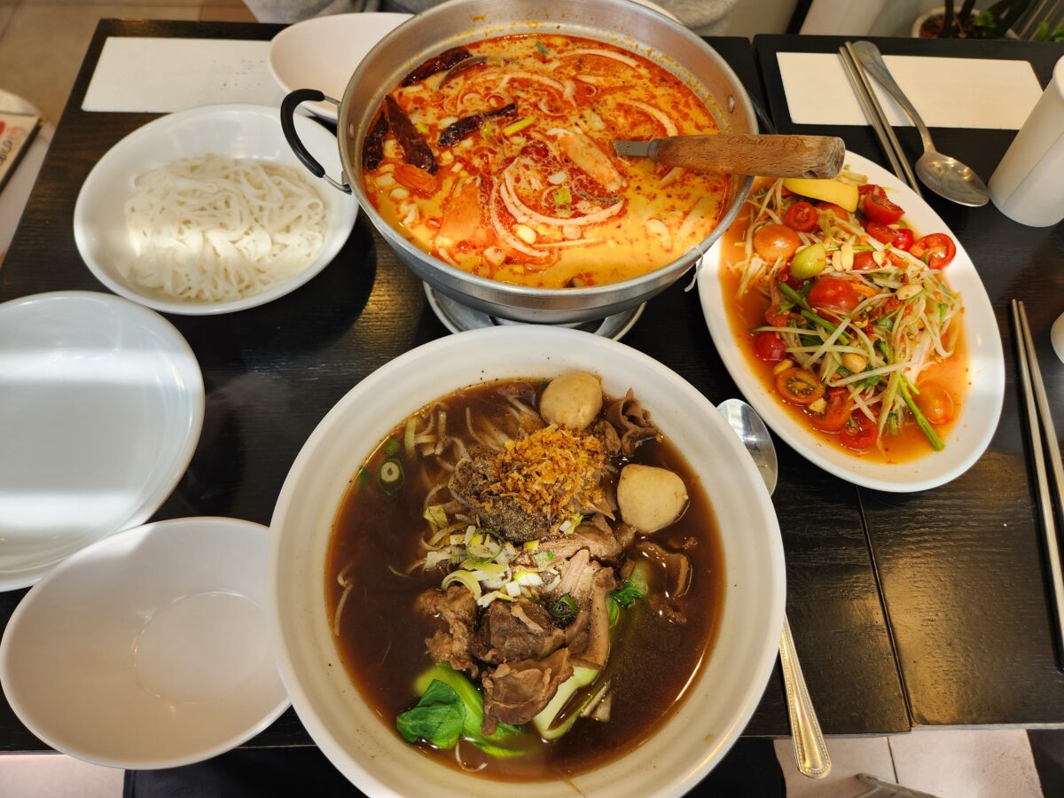 테이블 위에 돼지고기 쌀국수, 똠양꿍, 쏨땀이 차려져 있는 전체 샷.