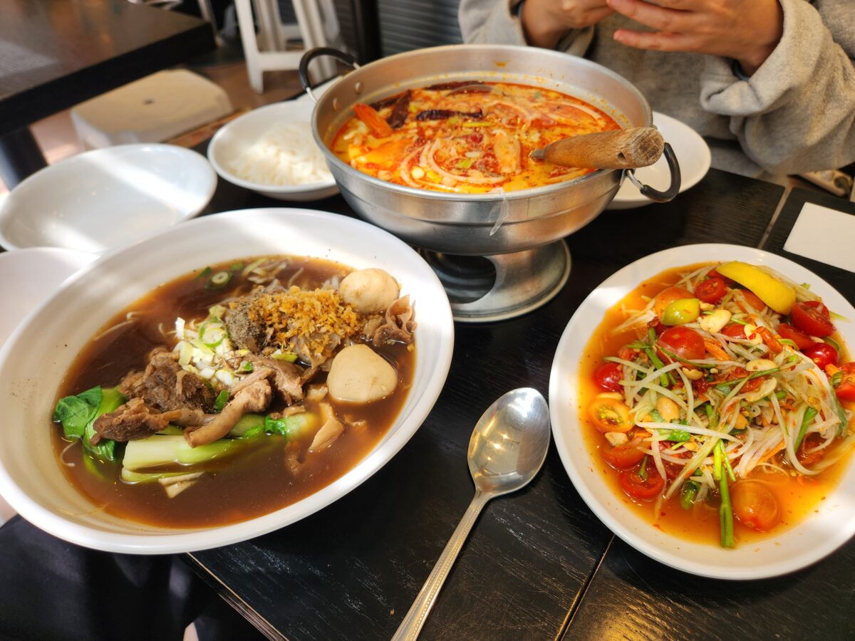 쌀국수, 똠양꿍, 쏨땀이 차려진 테이블 항공 샷.