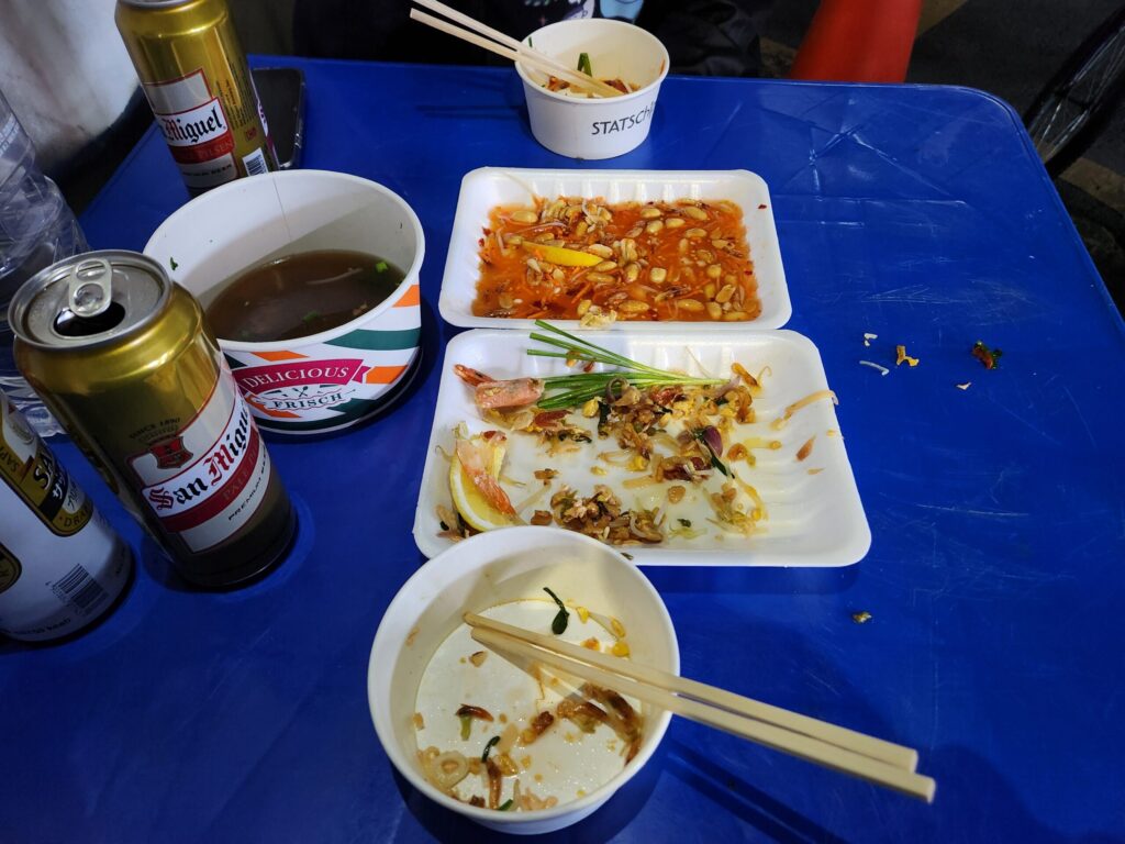 쌀국수, 팟타이, 쏨땀과 맥주가 모두 놓여 있는 테이블 전경