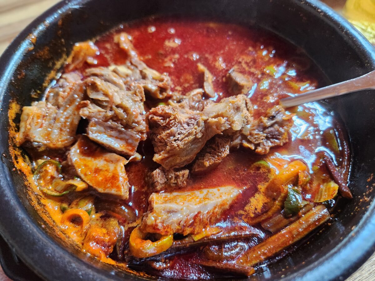 숟가락으로 고기를 들어 올린 얼큰한 비주얼의 육갈탕 근접샷