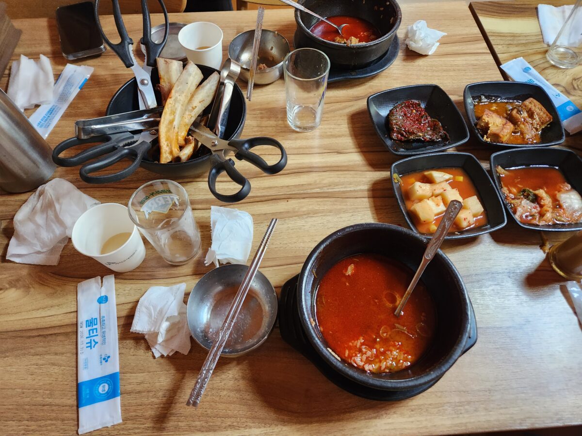 육갈탕을 먹고 난 후 빈 뚝배기와 가위, 집게, 밑반찬 접시들이 놓인 테이블