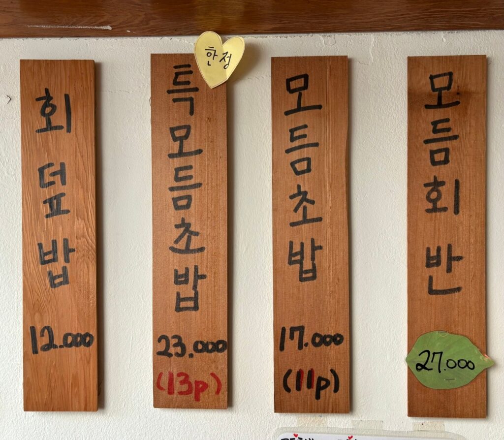 벽에 걸린 특모듬초밥, 모듬회 등 메인 메뉴 가격이 적힌 목재 메뉴판. (출처: 네이버 지도 업체 등록 사진)