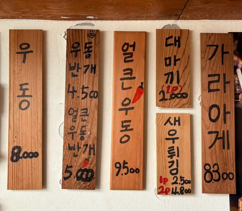 벽에 걸린 우동, 마끼, 새우튀김 등 사이드 메뉴가 적힌 목재 메뉴판. (출처: 네이버 지도 업체 등록 사진)