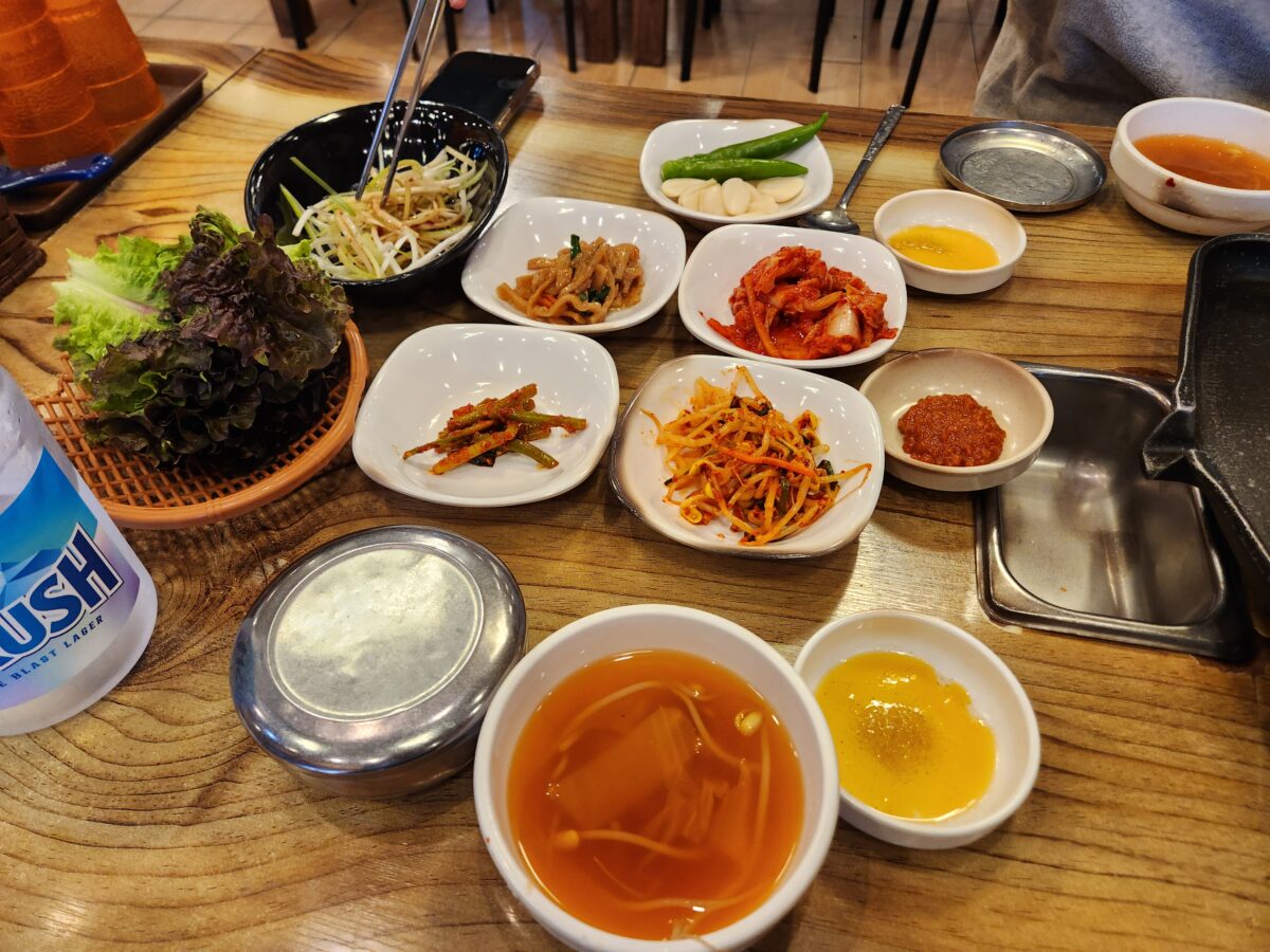 쌈채소, 파무침, 콩나물무침 등 다양한 반찬이 세팅된 테이블.