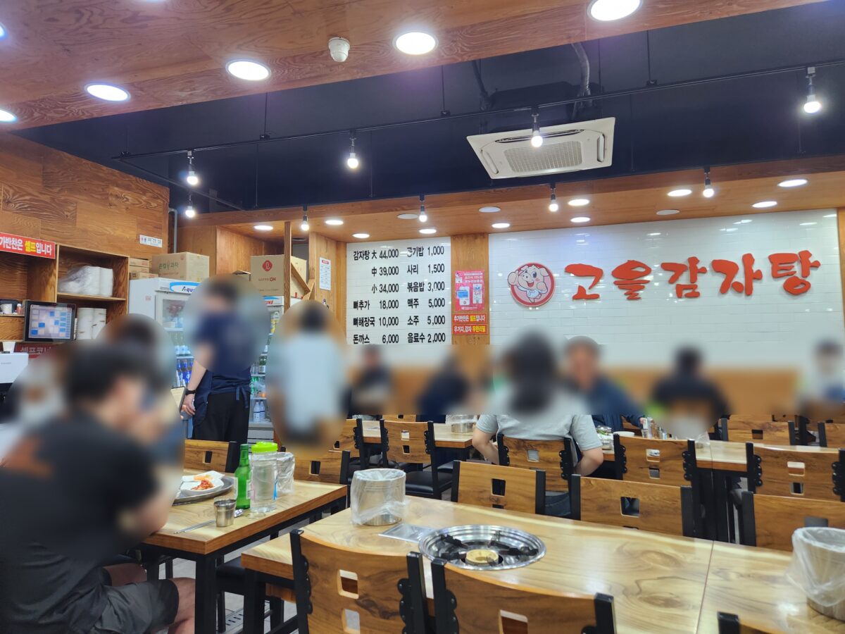 손님들로 북적이는 식당 내부와 벽면에 걸린 메뉴판.