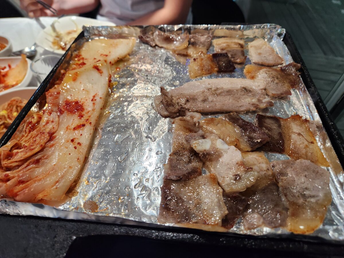 불판 위에서 노릇하게 익어가는 삼겹살과 김치