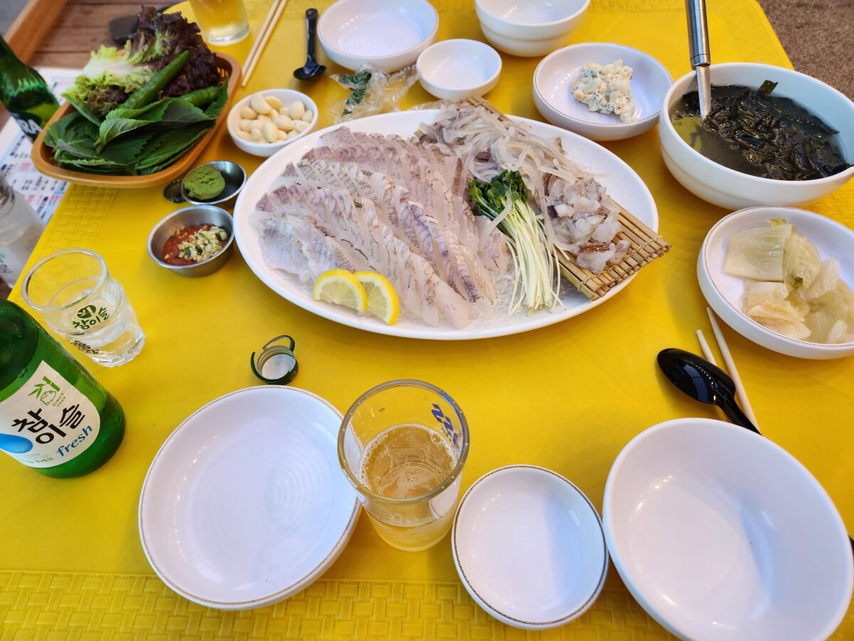 우럭회, 오징어회와 함께 미역국, 소스류 등 기본 상차림이 차려진 전체 테이블 샷.