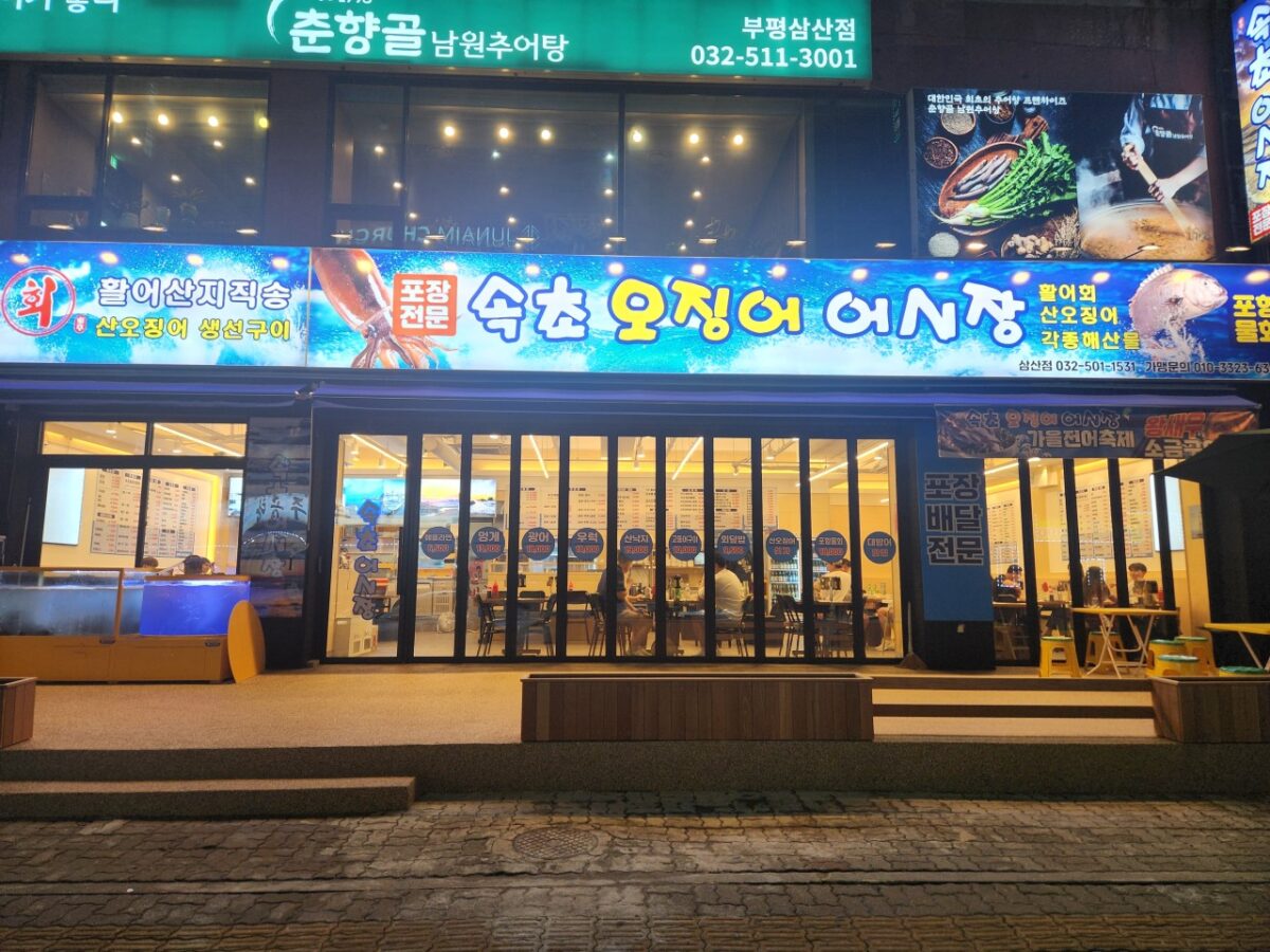 저녁 시간대 속초오징어어시장 삼산점 매장 외부 전경과 야장 좌석 모습.