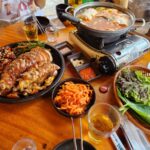 테이블 위에 차려진 반반 족발, 순두부찌개, 밑반찬, 소맥 잔