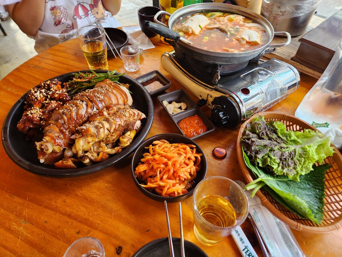 테이블 위에 차려진 반반 족발, 순두부찌개, 밑반찬, 소맥 잔