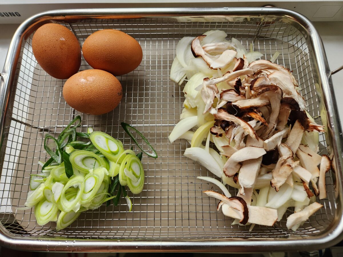 채반에 담긴 양파, 채 썬 대파, 참송이 버섯과 계란 3알.