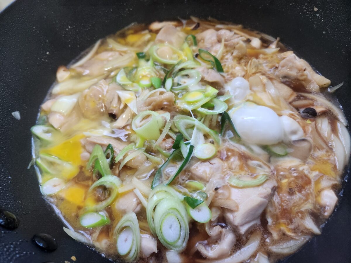 프라이팬 안의 재료들에 계란물이 1차로 부어져 익어가는 모습.