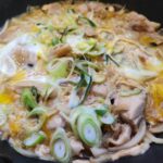 프라이팬 안에서 계란물과 닭고기, 파가 어우러져 익어가는 모습.