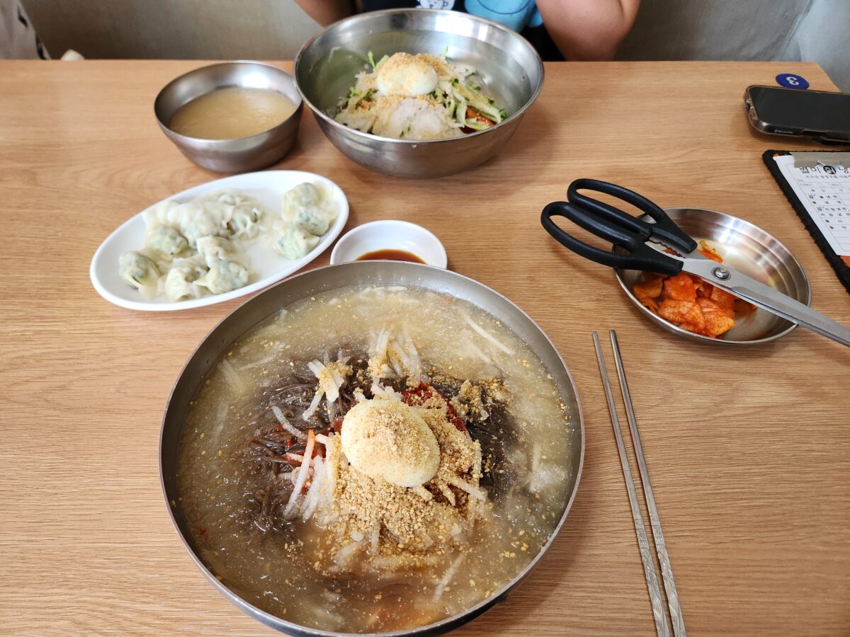 물냉면, 비빔냉면, 물만두, 무김치가 골고루 배치된 테이블 전체 항공샷.