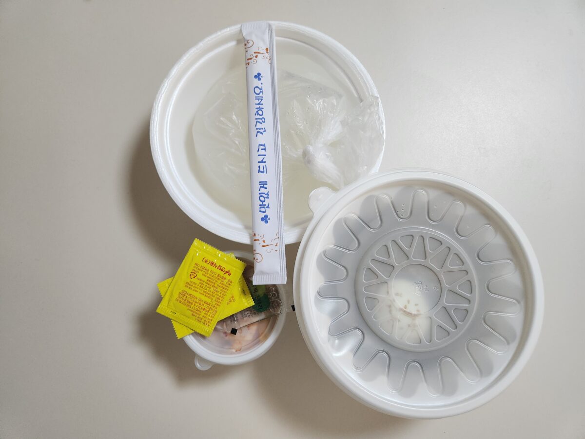 포장된 육수 봉지, 식초, 겨자, 일회용 젓가락이 놓인 포장 구성 전체 샷.