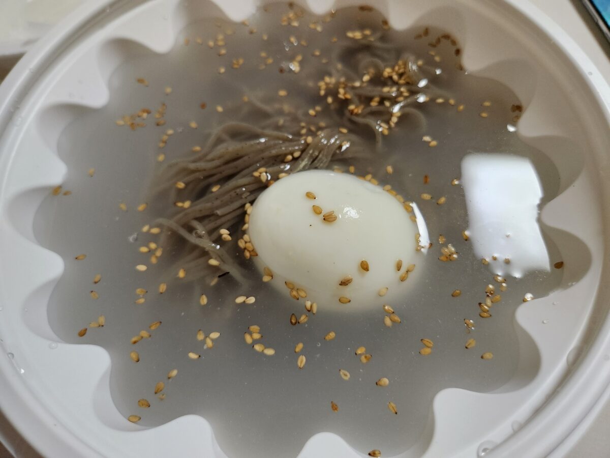 육수에 담긴 메밀면과 계란이 담긴 물막국수 클로즈업.