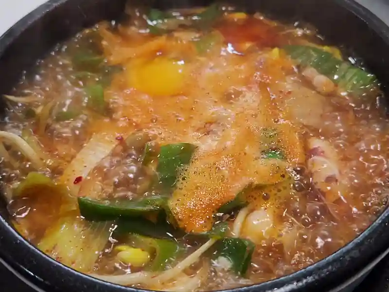 뚝배기 안에서 팔팔 끓고 있는 오징어해장국과 날계란 모습 gif.