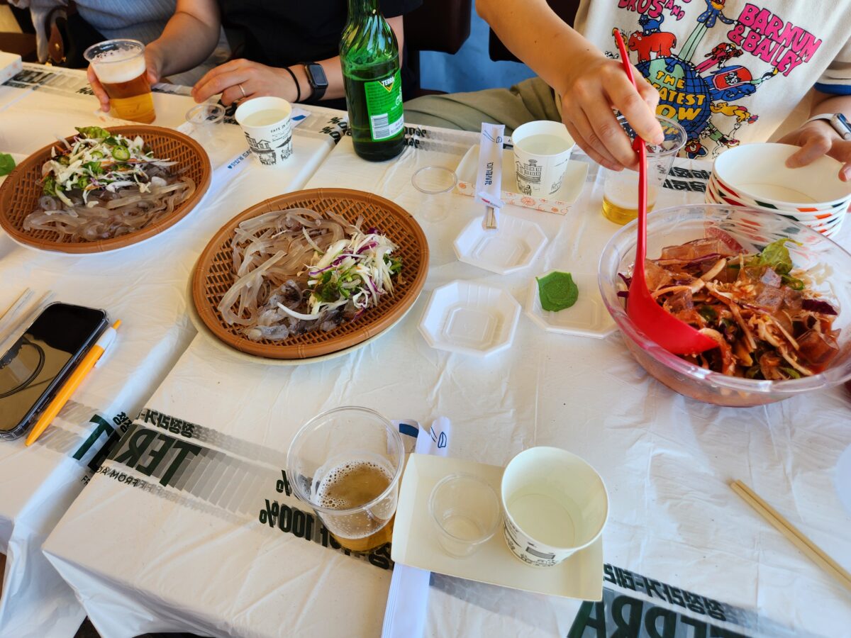 오징어 회와 물회가 차려진 오징어난전 테이블과 사람들.