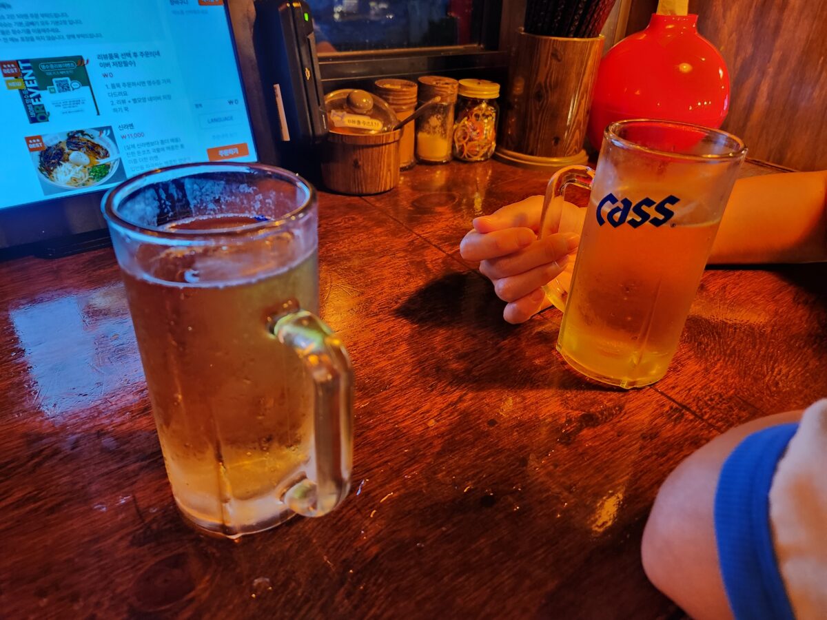 테이블 위에 놓인 시원한 생맥주 잔과 매장 내부 분위기.