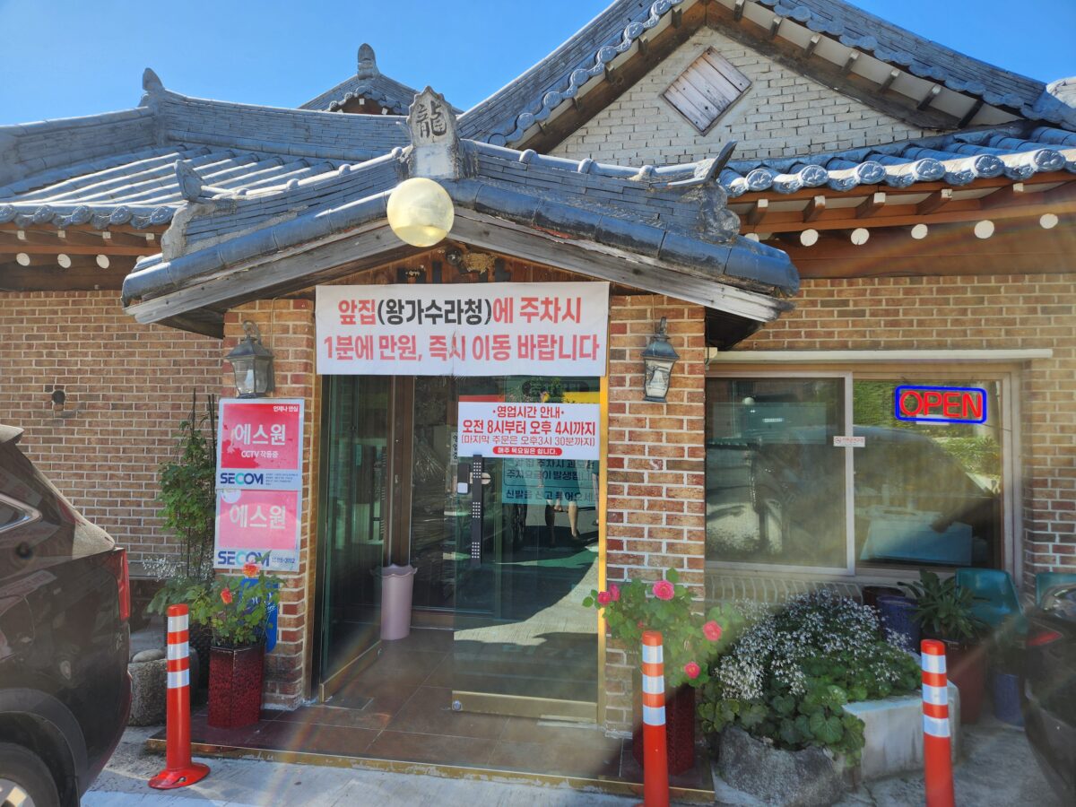 한옥 건물의 식당 입구와 주차 안내문이 붙은 모습.