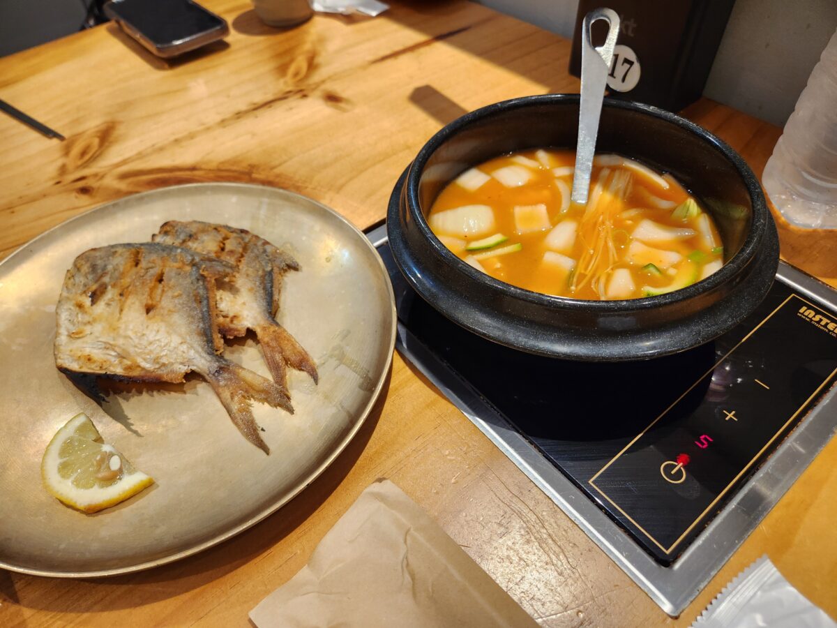 테이블 위에 놓인 병어구이 접시와 찌개 뚝배기.