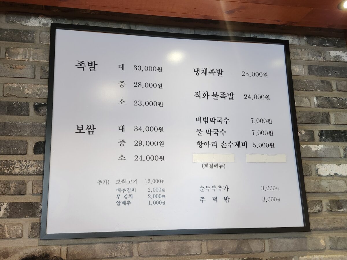 식당 내부 벽면에 부착된 장씨아궁이의 족발 및 보쌈 메뉴와 가격표.