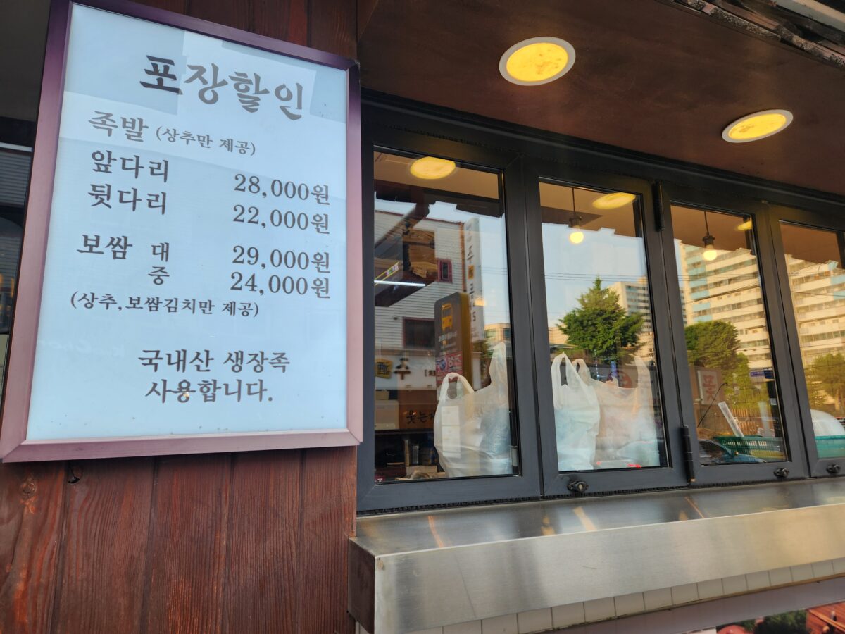 장씨아궁이 매장 입구에 안내된 포장 할인 메뉴 정보와 외부 창문.