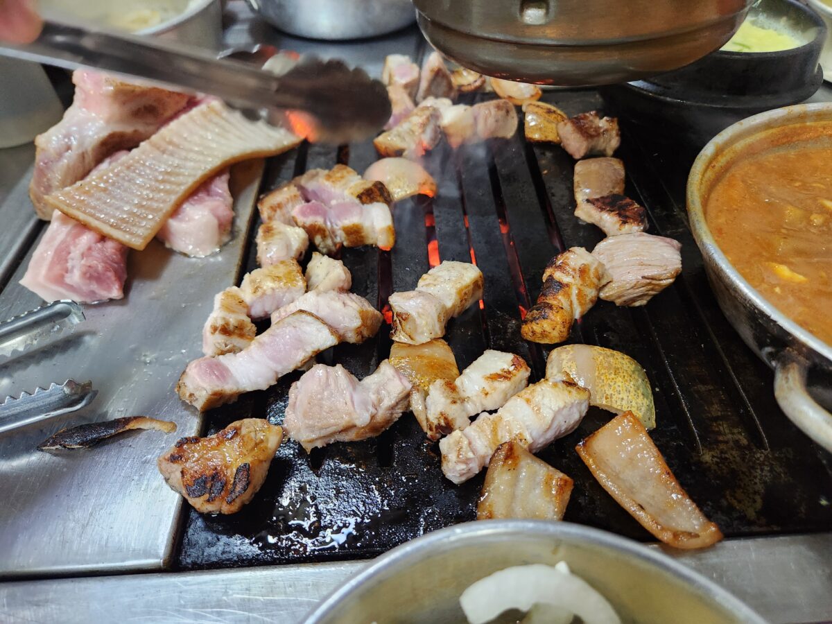 연탄 불판 위에서 구워지고 있는 주먹고기와 돼지껍데기.