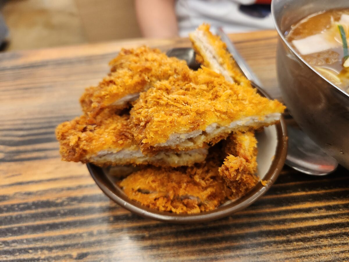 접시에 담긴 두툼하고 바삭한 돈까스