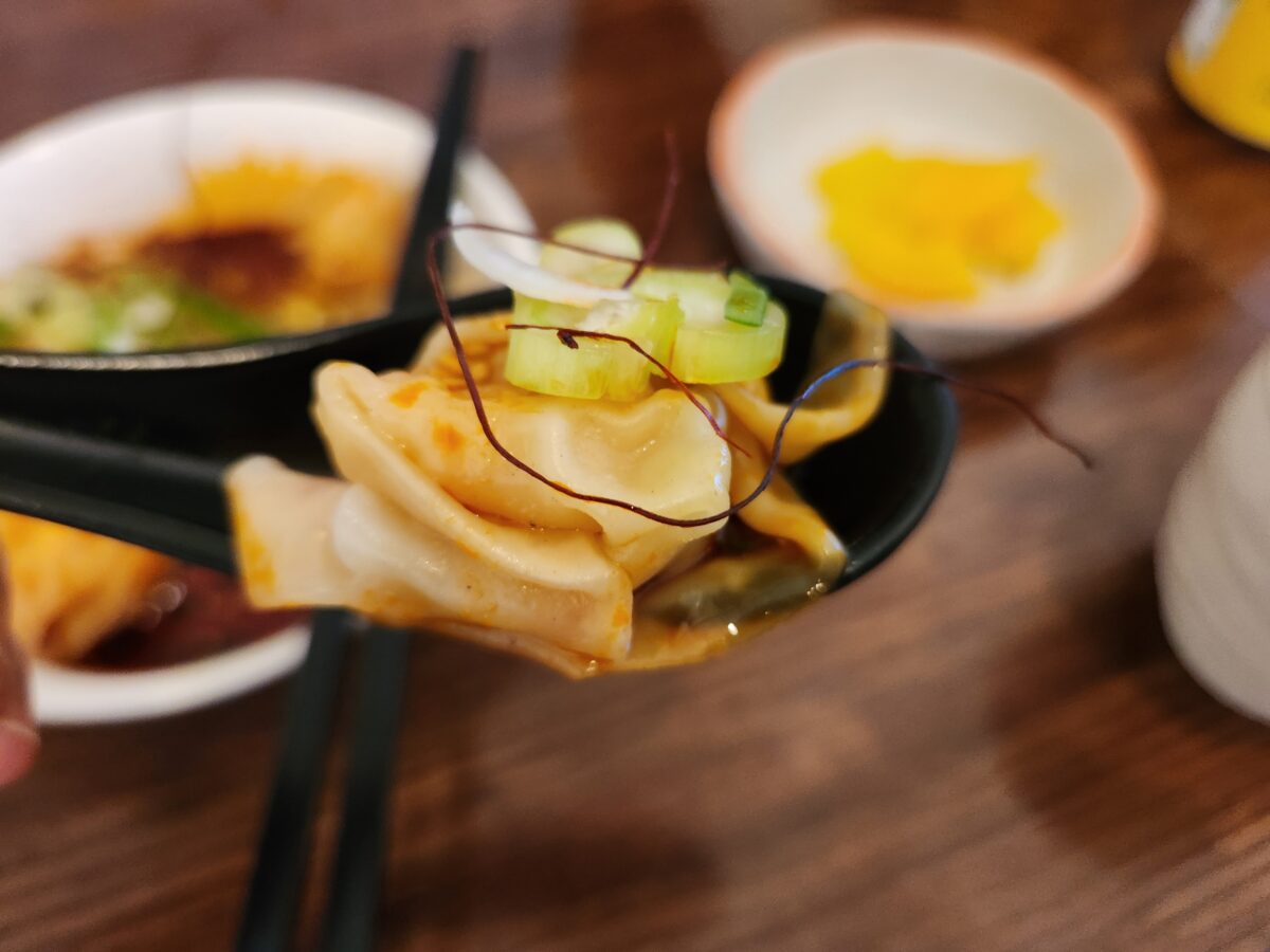 숟가락 위에 올려진 매콤비빔완탕 근접 샷.