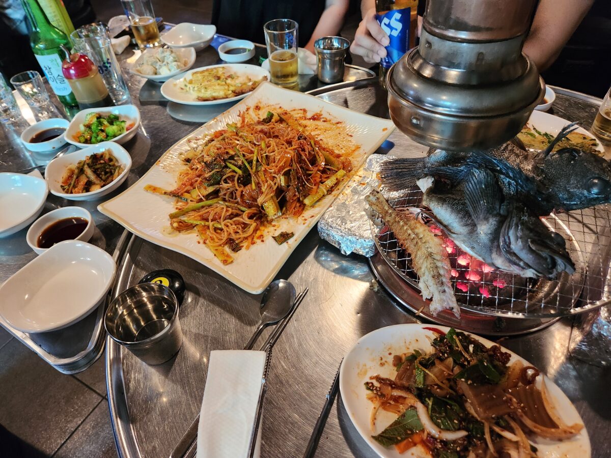 테이블 위에 차려진 쫄뱅이와 구워지고 있는 우럭 전경.