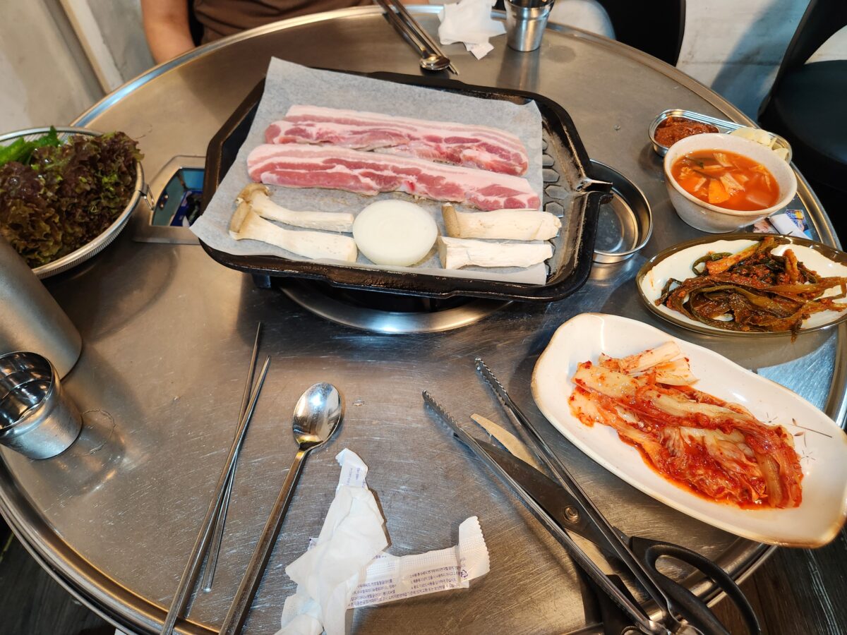 제주하루미삼겹살의 고기, 밑반찬이 차려진 전체 테이블 전경.